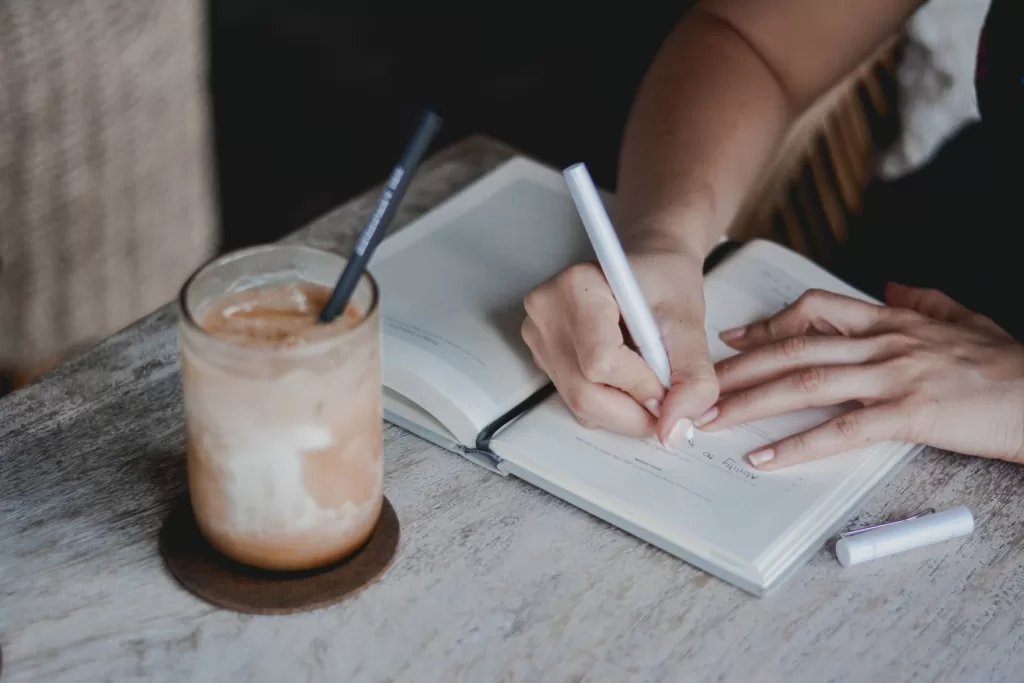 Woman writing in a notebook and setting her goals